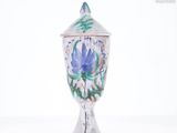 un vase sur lequel est peinte une fleur sur un fond blanc