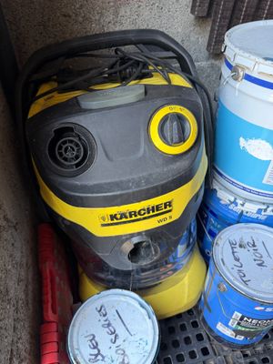 a yellow and black vacuum sitting next to buckets of paint