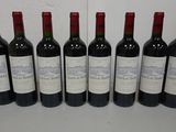 six bottles of red wine are lined up on a table