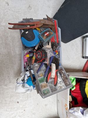 une valise remplie d'outils et un skateboard posé par terre
