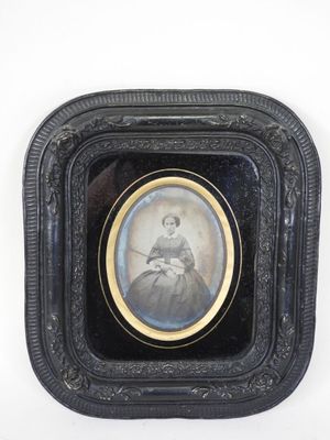 an old picture of a woman in a black dress in a black frame