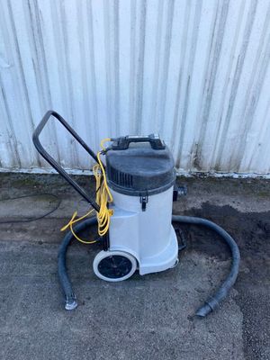a white and black vacuum sitting on top of a cement floor