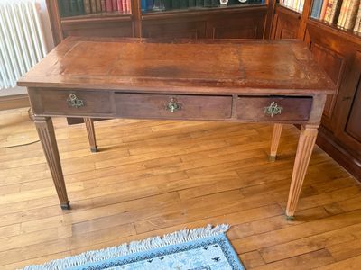 a wooden desk with two drawers and a blue rug