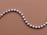 une image représentant un collier orné d'un serpent, posé sur une surface marron