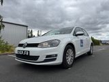 La voiture blanche est garée sur le parking près de l'immeuble.