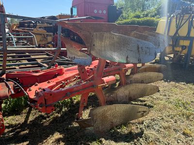 un tracteur immobilisé dans l'herbe, avec une charrue attelée derrière lui