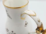 a white and gold coffee pot with a gold handle