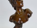 buste en bronze d'une femme posé sur un socle, sur fond blanc