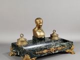une statue représentant un homme assis sur un bureau en marbre