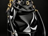 a black bucket bag with gold hardware on a black background