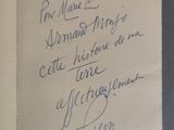 un livre ouvert, sur lequel est inscrit un poème manuscrit, posé sur une table