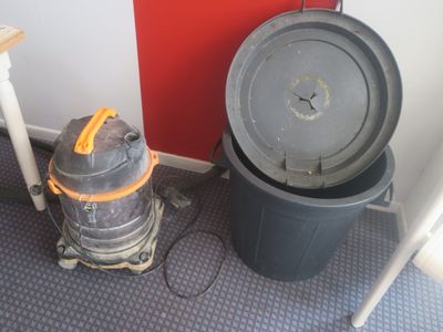 une poubelle posée à côté d'une autre poubelle, par terre