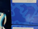 une figurine de vache posée sur une table, à côté d'une boîte bleue