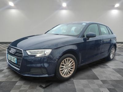 Une Audi bleue est garée sur un sol à damier dans un garage.