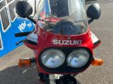 une moto Suzuki rouge garée devant un bus