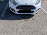 a white car parked in a parking lot next to a wall