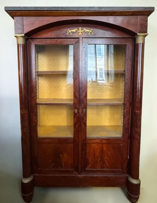 a large wooden cabinet with glass doors and a clock on top