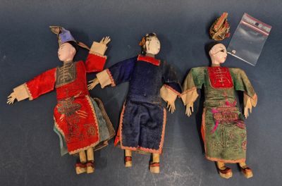 trois poupées en tissu représentant des personnes d'origine asiatique, allongées sur une table