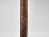 an old wooden stick with a design on it sitting on a white surface