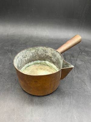 a metal pan with a wooden handle on a table