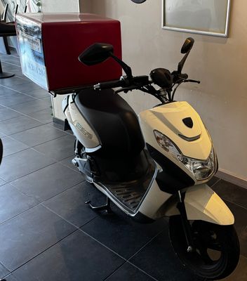 a scooter that is parked in a room with pictures on the wall