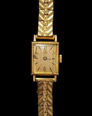 une image montrant un gros plan d'une montre en or sur fond noir