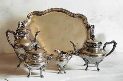 trois théières en argent et un plateau posés sur une table