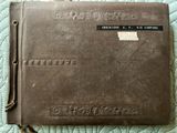 an old brown leather book sitting on top of a quilted bed