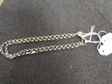 une chaîne en argent à laquelle est accrochée une médaille, posée sur une table