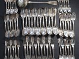 de nombreuses cuillères et fourchettes en argent disposées sur une table