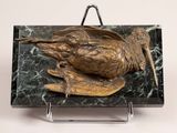 bronze sculpture of a bird sitting on a marble block