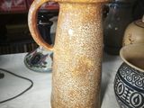 a brown vase sitting on a table with a white table cloth