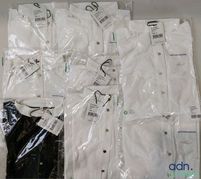 Plusieurs chemises blanches sont emballées dans des sacs en plastique posés sur une table