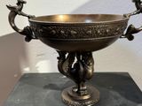 a large metal bowl with two birds on it on a table
