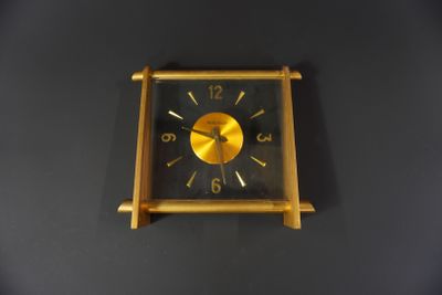 une horloge dorée sur un mur noir, avec un fond noir