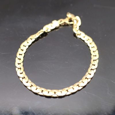 gros plan d'un bracelet en chaîne en or sur une surface noire