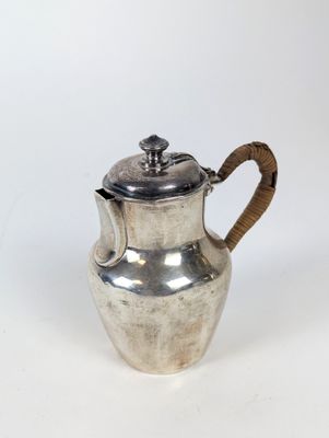 une théière ancienne en argent avec une anse en bois, sur fond blanc
