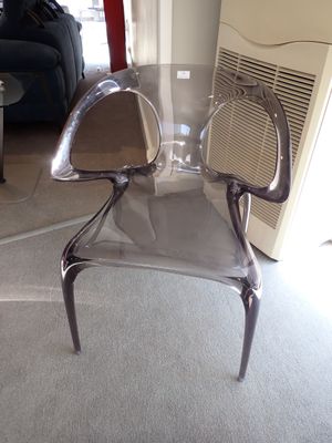 une chaise en plastique transparent posée au milieu d'un salon