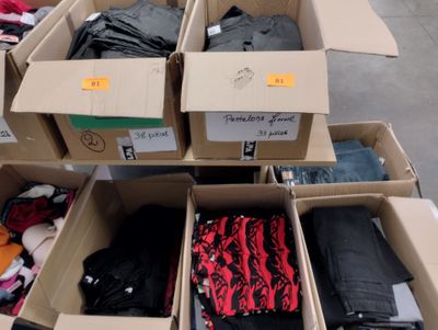 Plusieurs cartons de vêtements sont empilés les uns sur les autres
