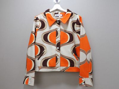 une veste orange et marron suspendue à un cintre accroché au mur
