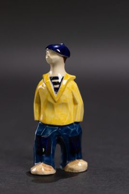 une petite figurine représentant un homme vêtu d'une chemise jaune et d'un pantalon bleu