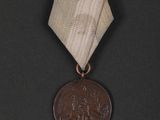 an old medal with a ribbon around it on a black surface