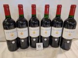 six bottles of red wine are lined up on a table
