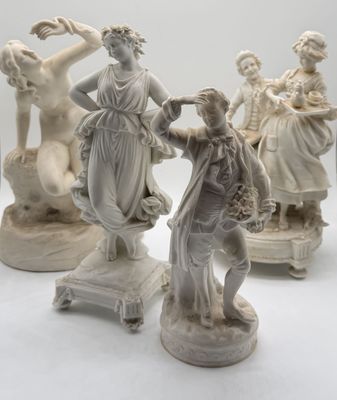 three white statues of women and a man on a white surface