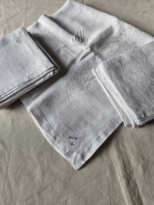 three folded napkins on a bed with a monogrammed design