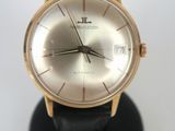 a gold watch on a black stand on a white surface