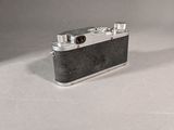 an old camera sitting on top of a white table next to a bottle