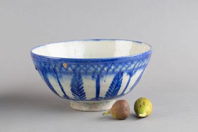 un bol bleu et blanc et quelques fruits sur la table