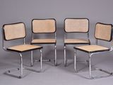 quatre chaises de salle à manger en chrome et rotin alignées sur un fond gris