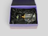 une image représentant un flacon de parfum en verre dans une boîte violette